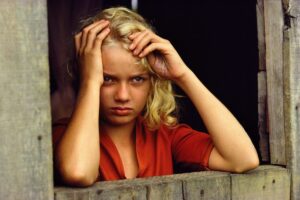 A woman in red shirt holding her head.
