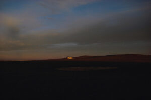 A house in the distance at night with dark clouds.