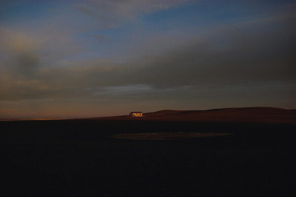 A house in the distance at night with dark clouds.