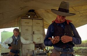 A man in a cowboy hat and vest holding something.