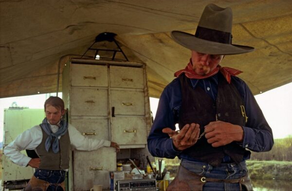 A man in a cowboy hat and vest holding something.