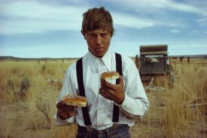 A man holding two sandwiches in his hands.