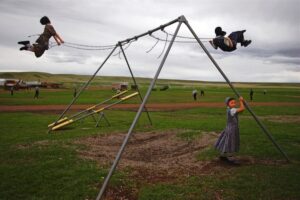 A group of people playing on an outdoor swing set.