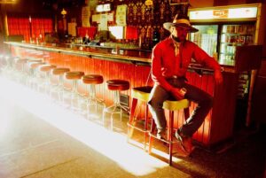 A man sitting on top of a bar in front of a counter.