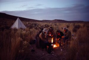 A group of people sitting around a fire in the desert.