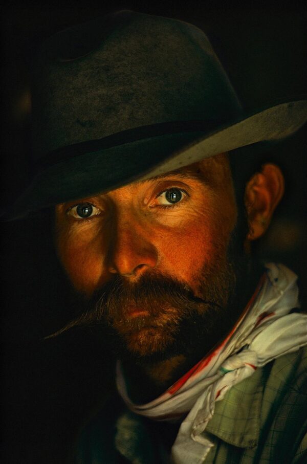 A man with a hat and mustache smoking a pipe.