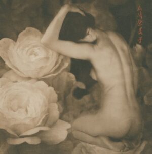 A nude woman sitting on the ground next to flowers.