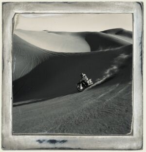 A person riding a motorcycle on top of a sand dune.