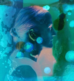 A woman with blue hair and ear buds in her ears.