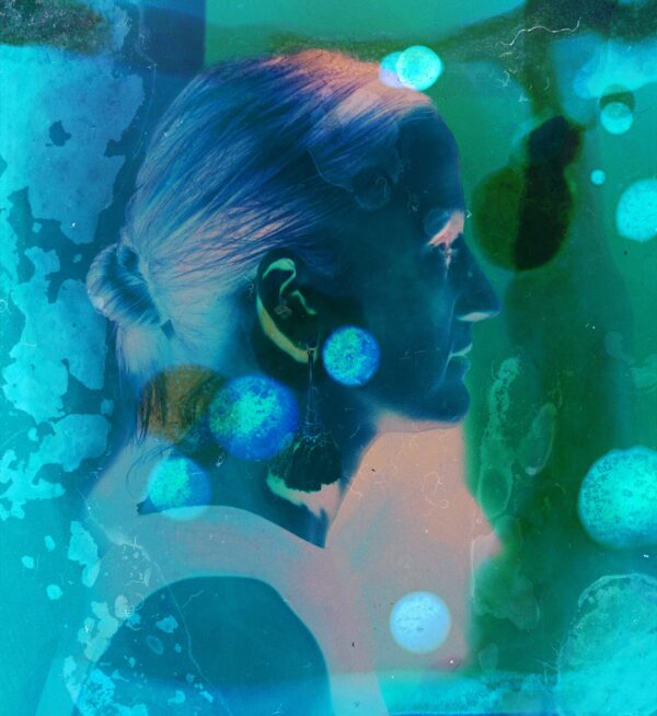 A woman with blue hair and ear buds in her ears.
