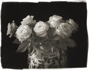 A black and white photo of some roses in a vase