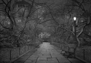A black and white photo of a walkway at night.
