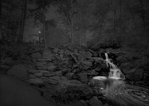 A waterfall in the middle of a forest at night.