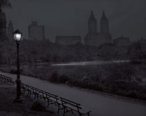 A bench and lamp in the dark near water.