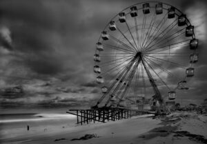 A ferris wheel on the beach with dark clouds in the background.