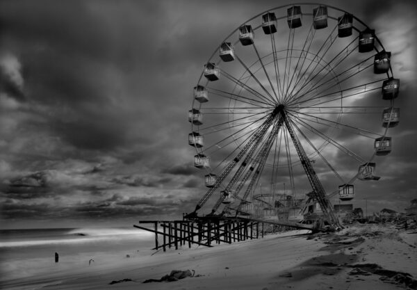 A ferris wheel on the beach with dark clouds in the background.