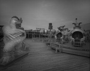 A black and white photo of some statues on the boardwalk.