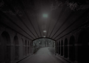 A dark tunnel with arches and lights on the side.
