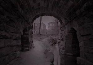 A dark picture of an old tunnel with a person walking through it.
