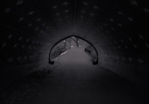 A dark tunnel with lights on the side.