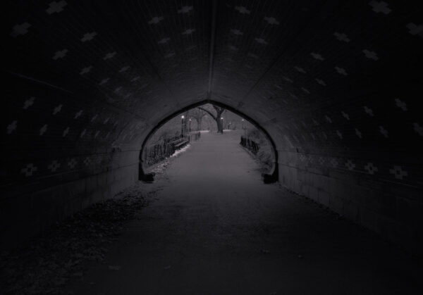A dark tunnel with lights on the side.