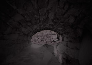 A dark cave with a rock wall and a light.