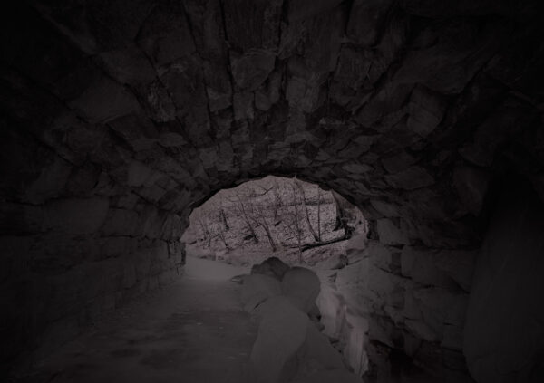 A dark cave with a rock wall and a light.