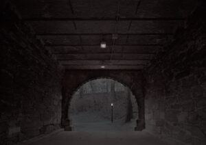 A dark tunnel with lights on the side.