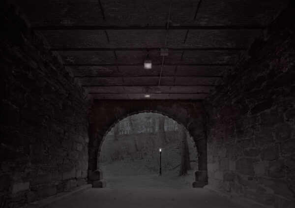 A dark tunnel with lights on the side.