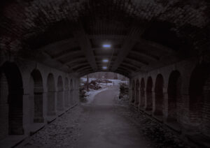 A tunnel with arches and lights on the side.