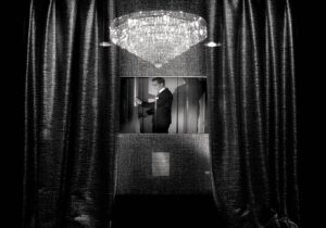 A man in suit and tie standing next to a window.