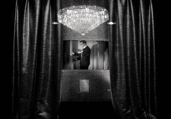 A man in suit and tie standing next to a window.