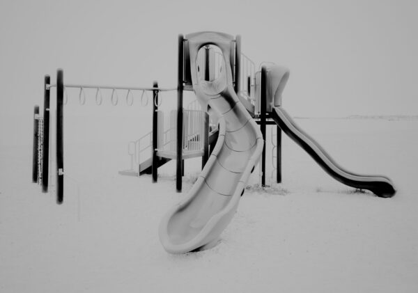 A black and white photo of a playground in the snow.