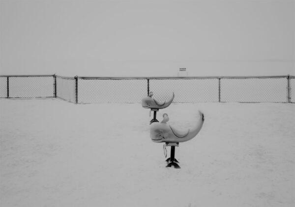 A black and white photo of two benches in the snow.