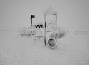 A black and white photo of some snow covered playgrounds.