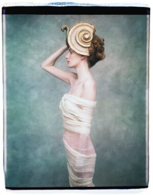 A woman in white dress with a hat on her head.