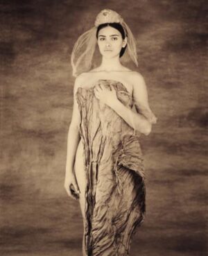 A woman in a dress with veil standing on the ground.