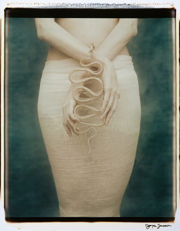 A woman holding a long snake in her hand.