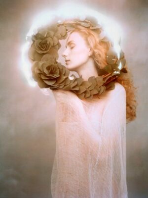 A woman with blonde hair and roses around her neck.