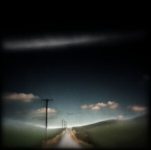 A road with power lines and clouds in the sky.
