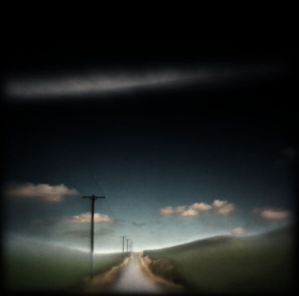 A road with power lines and clouds in the sky.