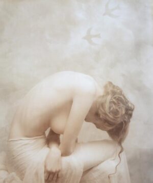 A woman sitting on the ground with her hands behind her head.