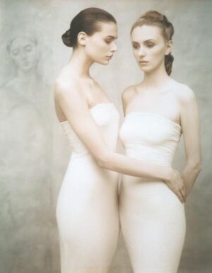 Two women in white dresses holding each other