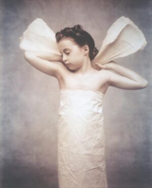 A young girl dressed in white with wings on her head.