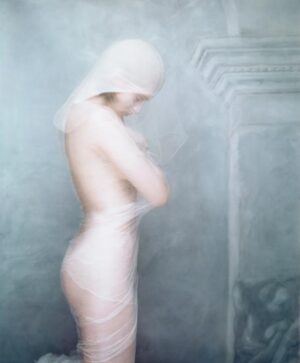 A woman in white underwear standing next to a wall.