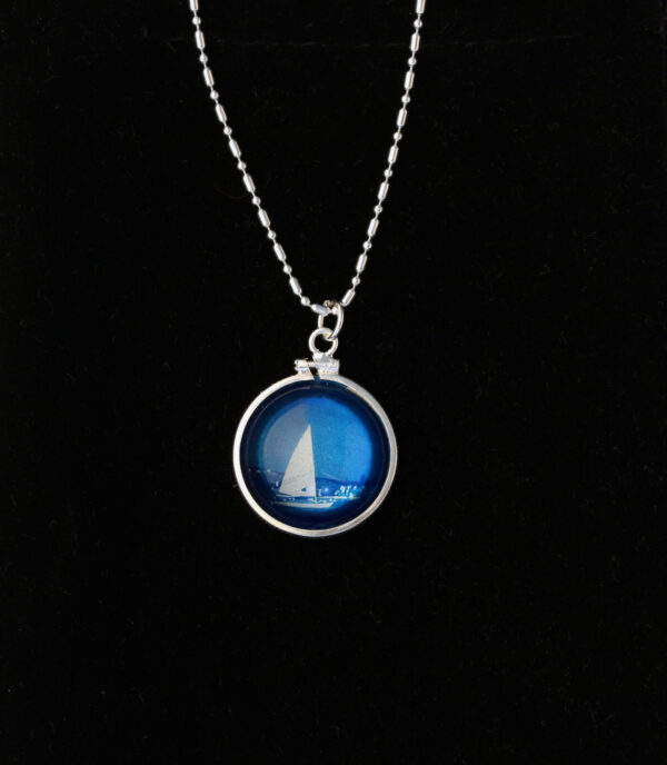 A necklace with a picture of a sailboat on it.