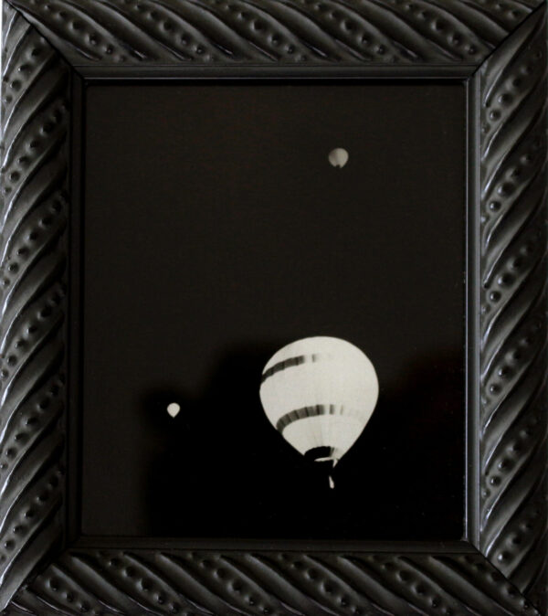 A black and white picture of a balloon in the sky