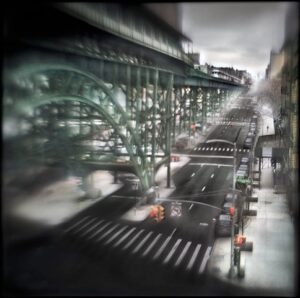 A blurry picture of an intersection with cars and people.