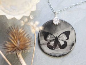 A butterfly is sitting on the side of a necklace.