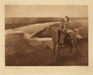 A man on horseback in the field near water.